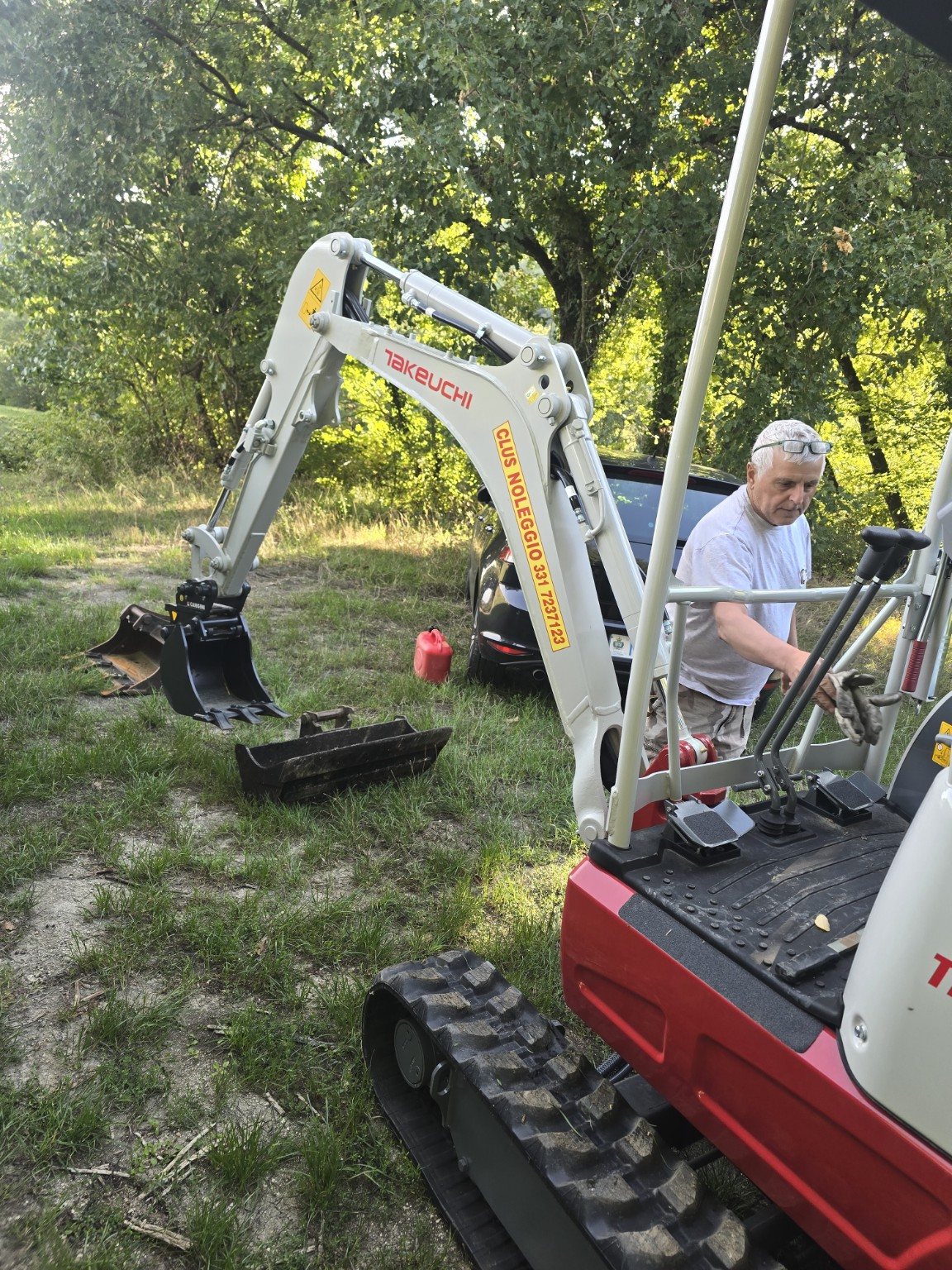 Braccio e benna del Takeuchi TB217R CLUS con attrezzature visibili a terra